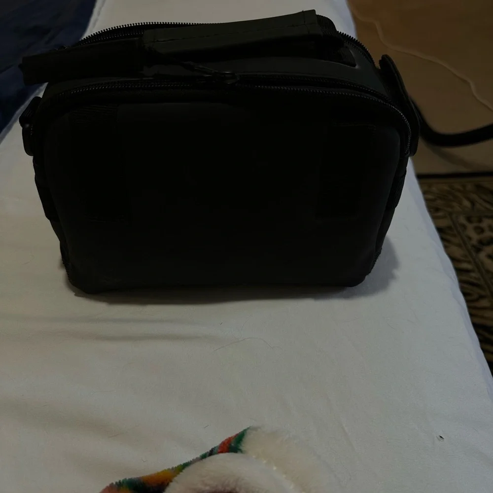 Canon black camera bag with zipper packets, and a handle at the top.